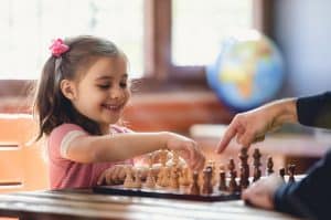 Father Teaching His Daughter to Play Chess At Home