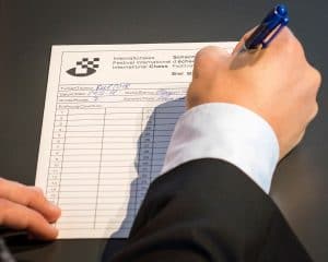 Man writing down chess notations on a scoresheet