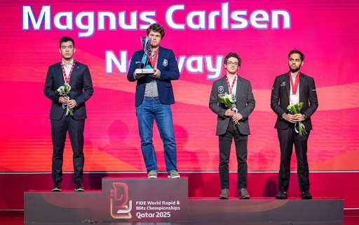 Magnus Carlsen holding his World Blitz Trophy on the podium along with other medalists as a Chess Highlight 2025