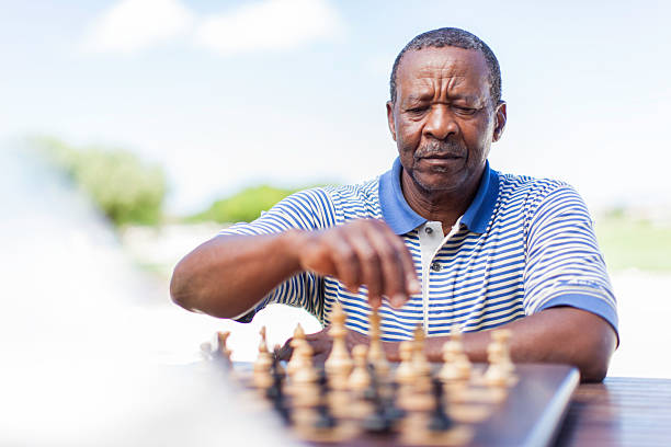 African senior sitting down, playing a game of chess against his friend in Langebaan, Western Cape, South Africa.