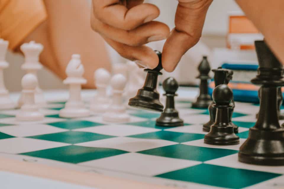 Closeup of hand moving a black chess piece on the chessboard